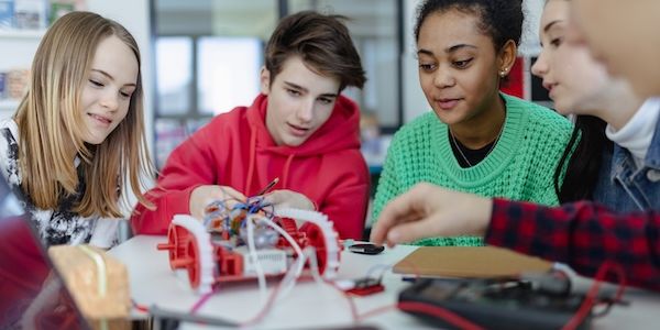 Group of high school students building and programming electric toys and robots at robotics classroom